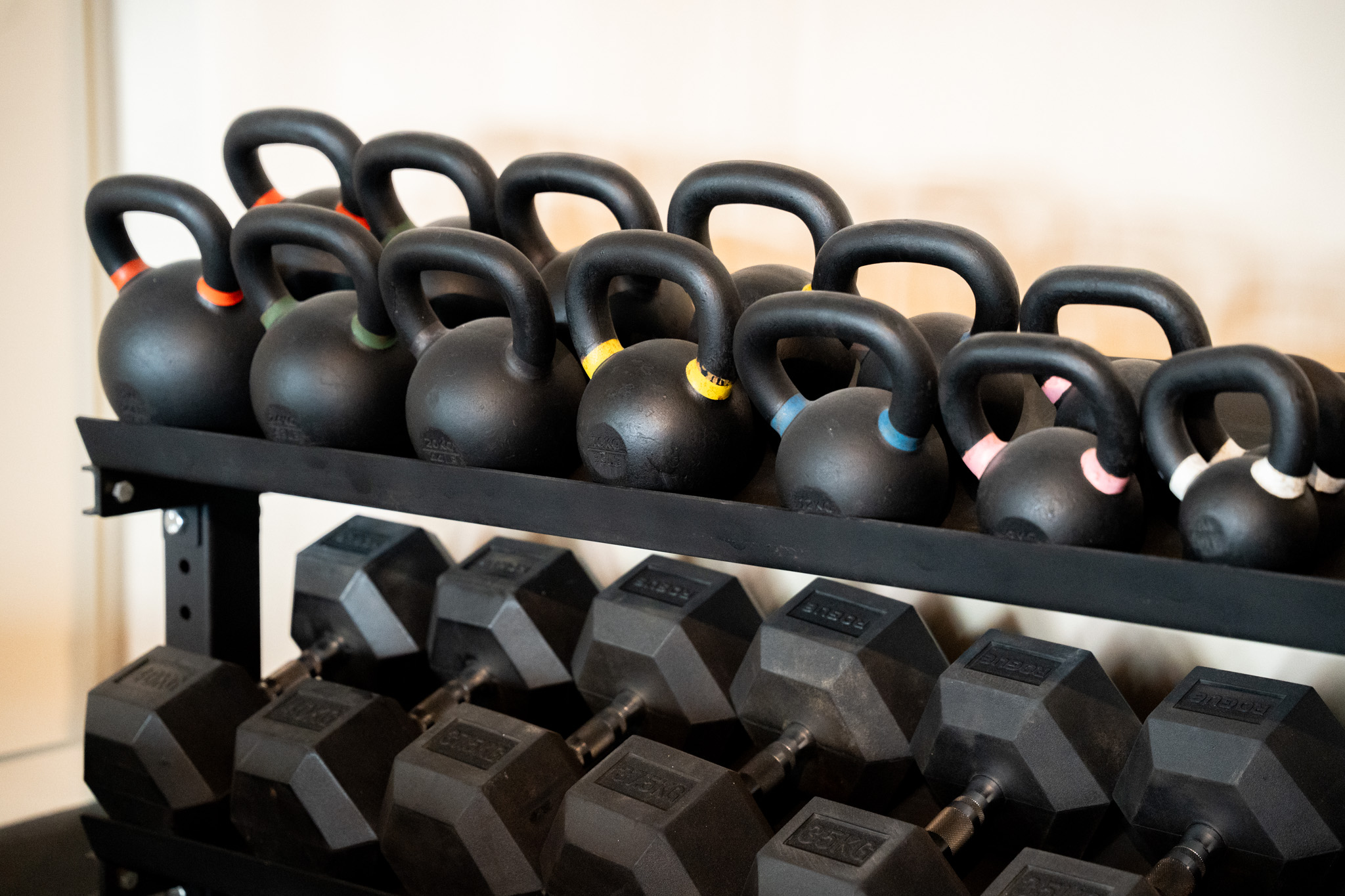 freddies studio bussum brede rij kettlebells met gekleurde grepen boven dumbbellrek