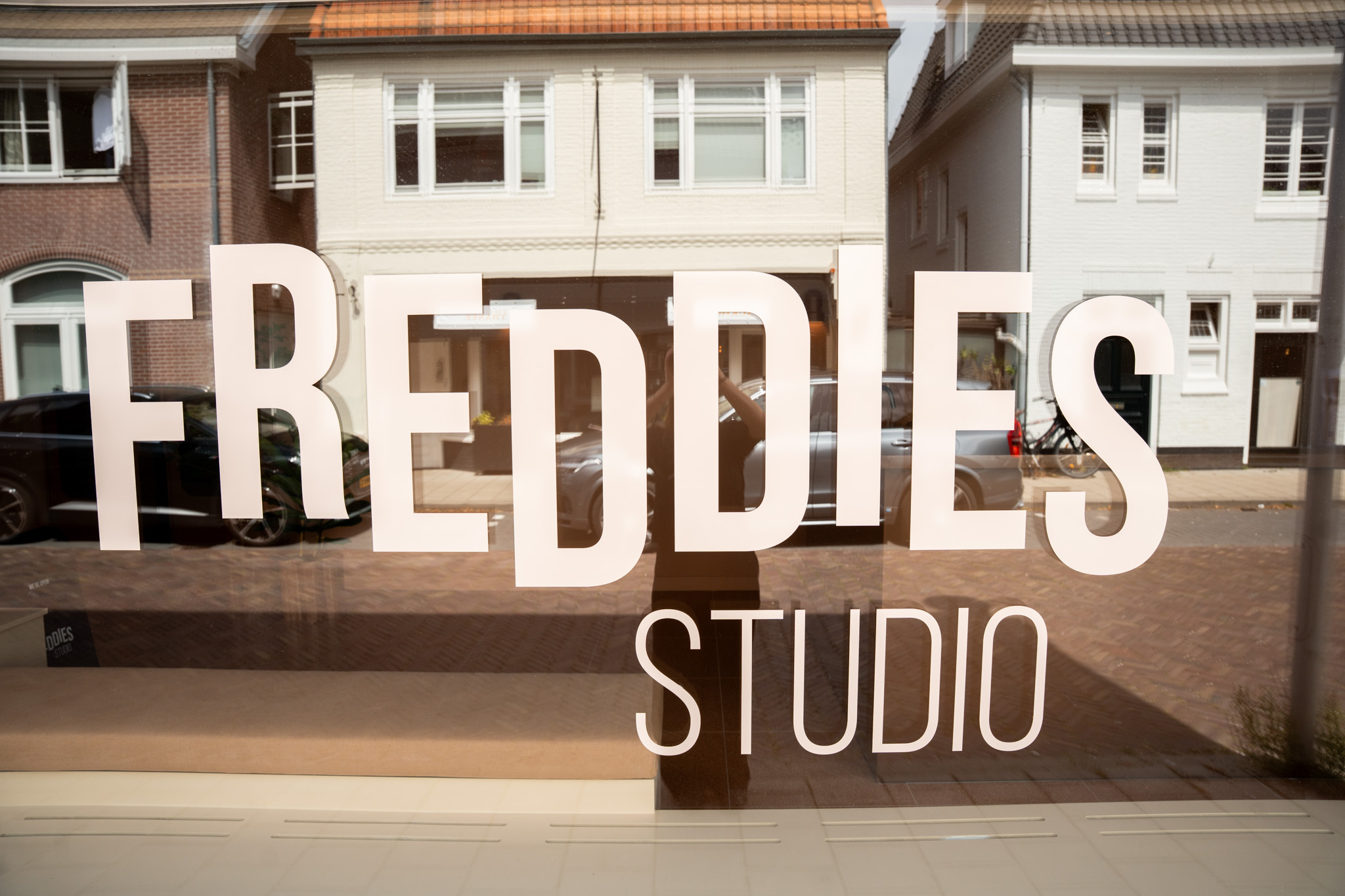 freddies studio bussum close up etalageraam met logo en spiegeling huizen en fietsen