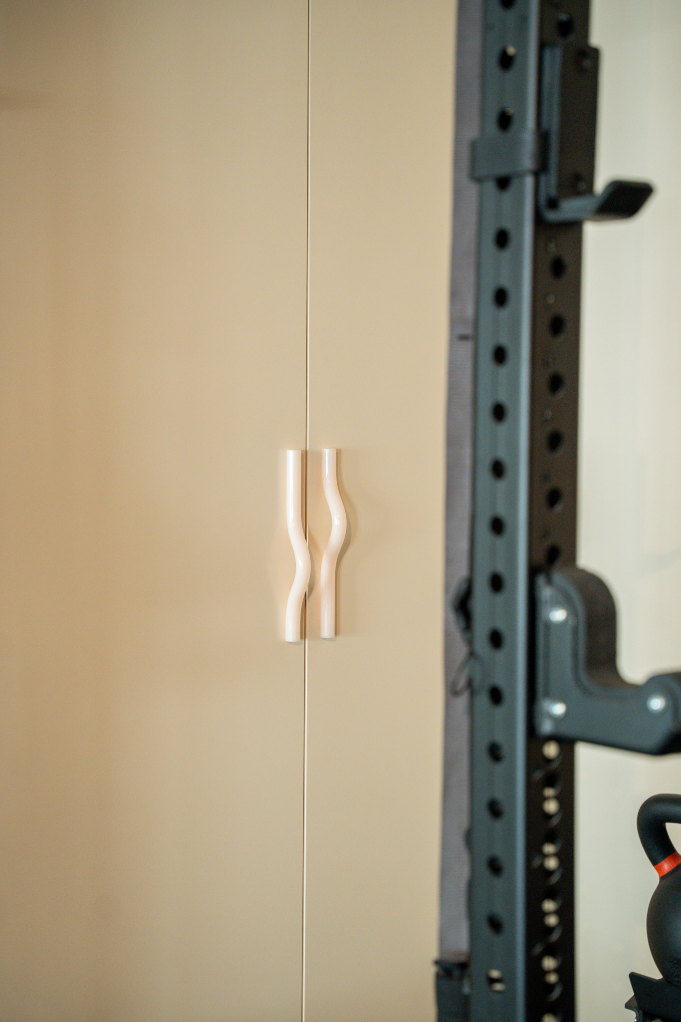 freddies-studio-bussum-close-up-golvende-witte-kastgrepen-naast-power-rack-met-kettlebell