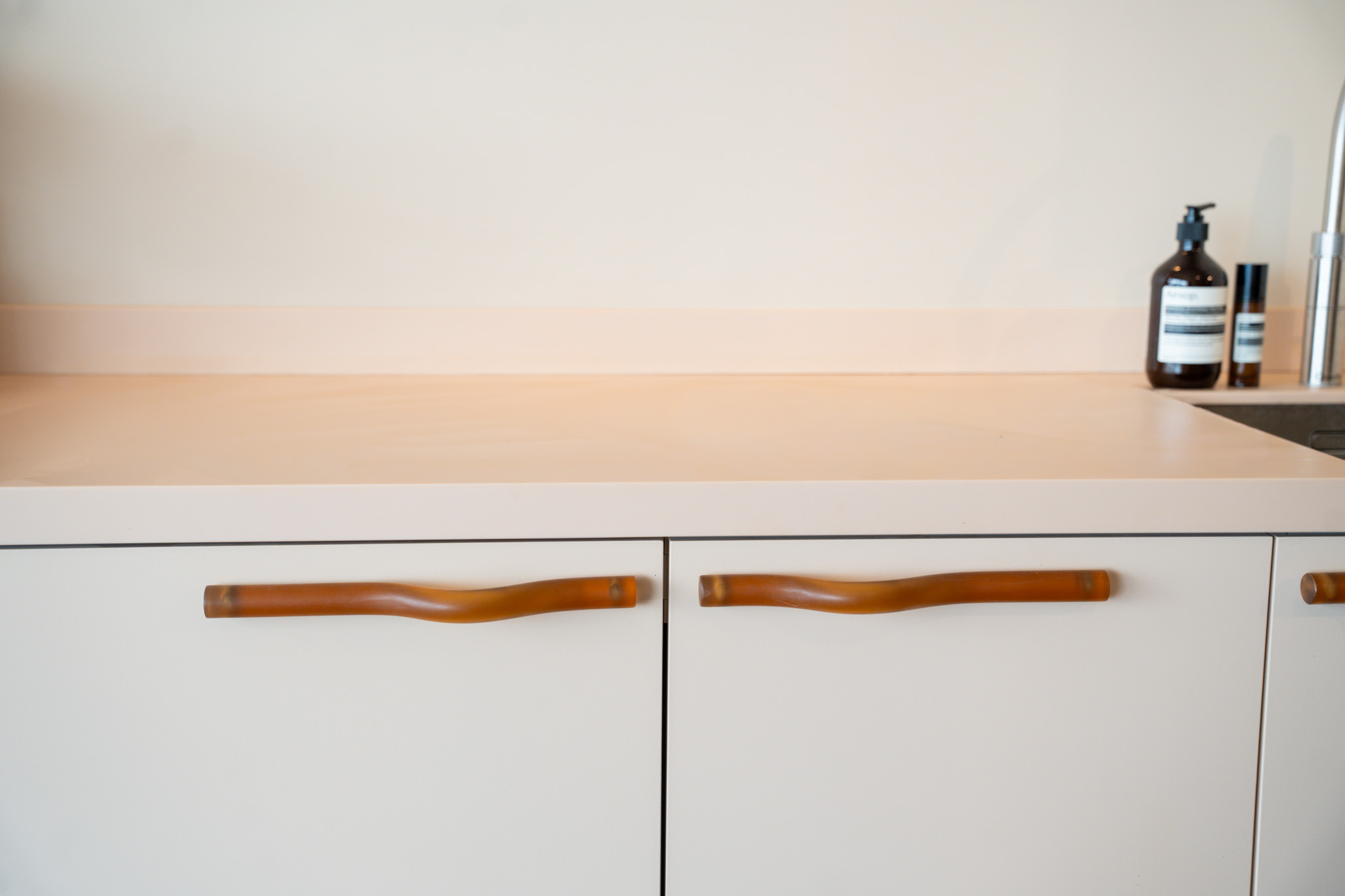 freddies studio bussum close up lederen kastgrepen op witte keukenkasten bij wastafel