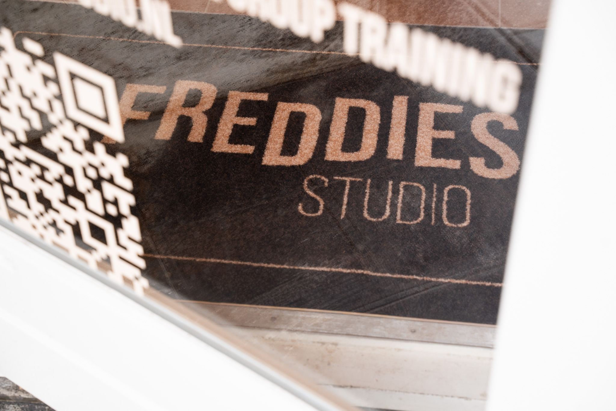 freddies studio bussum close up raamtekst logo met qr code en spiegeling deurmat andere hoek
