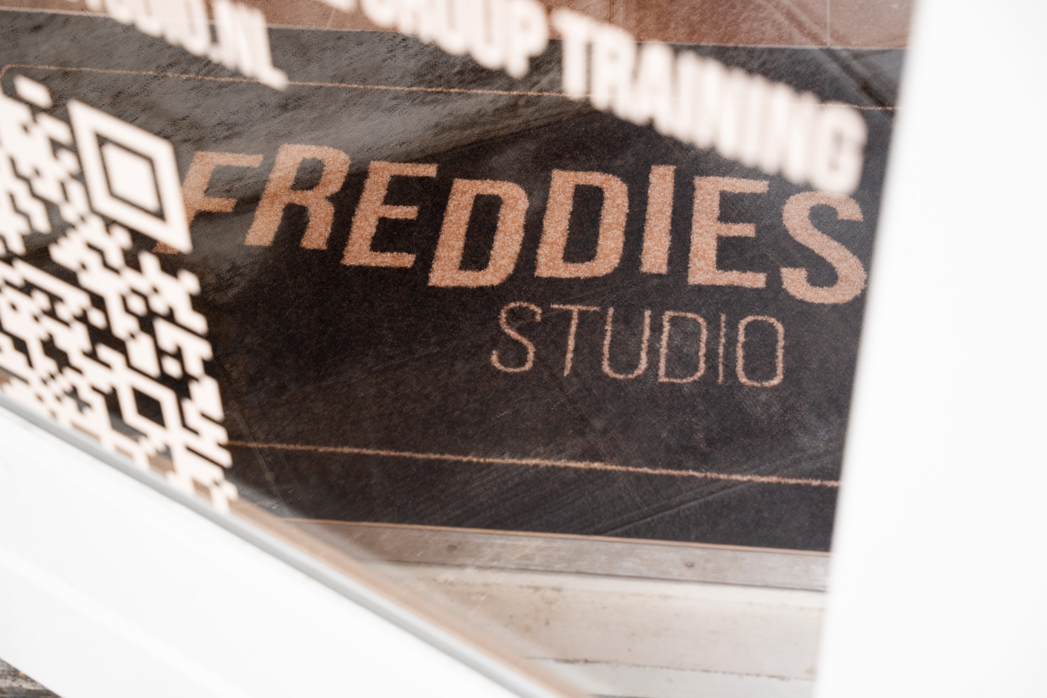 freddies studio bussum close up raamtekst logo met qr code en spiegeling deurmat