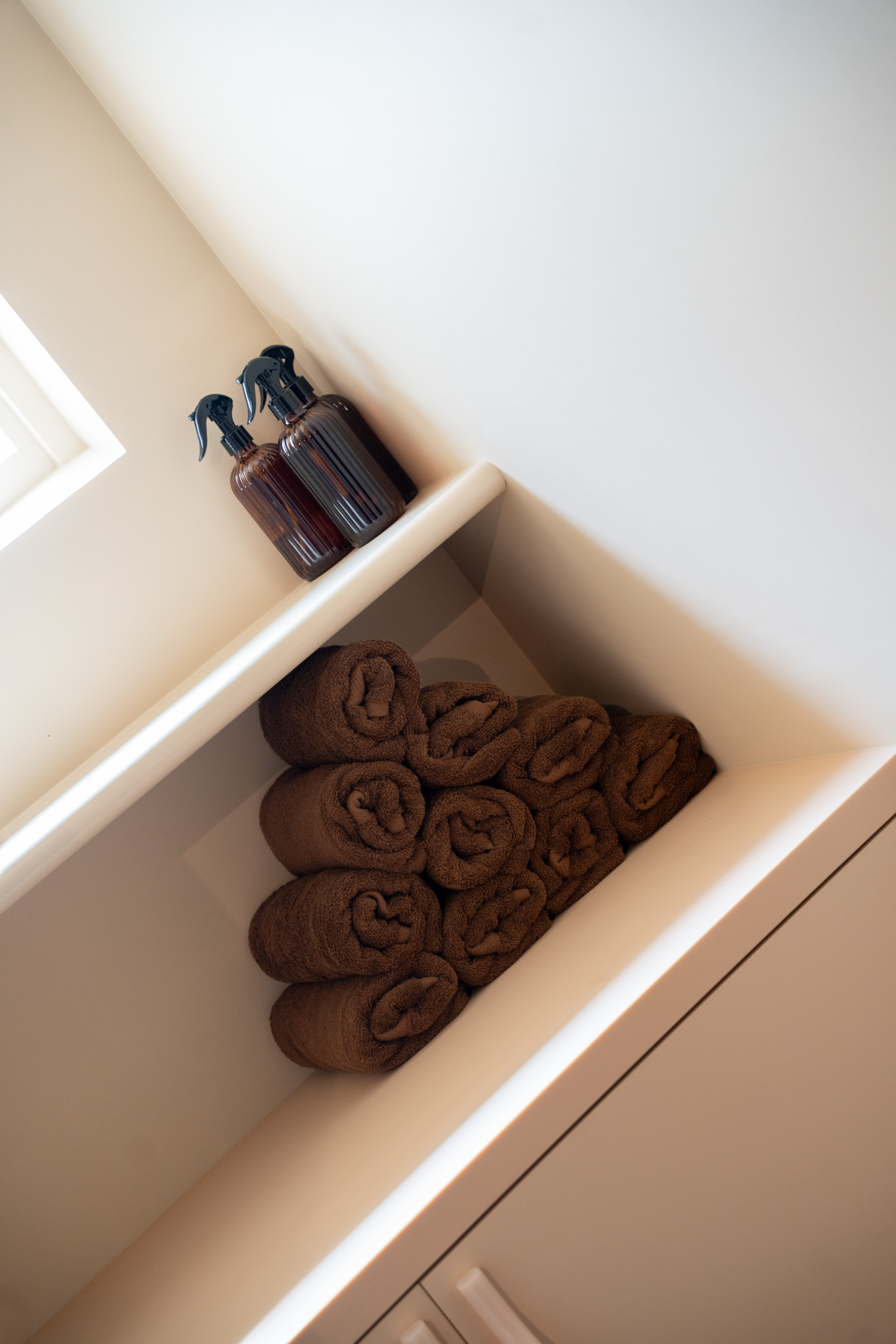 freddies-studio-bussum-close-up-sprayflacons-en-opgerolde-handdoeken-in-nis-bij-dakraam
