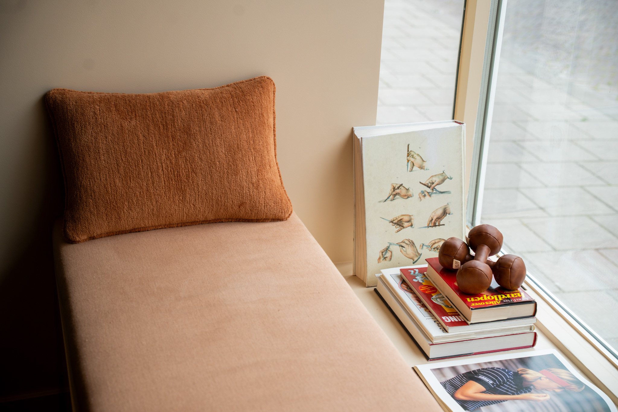 freddies studio bussum close up terracotta kussen zitbank met dumbbells boeken en opengeslagen tennismagazine