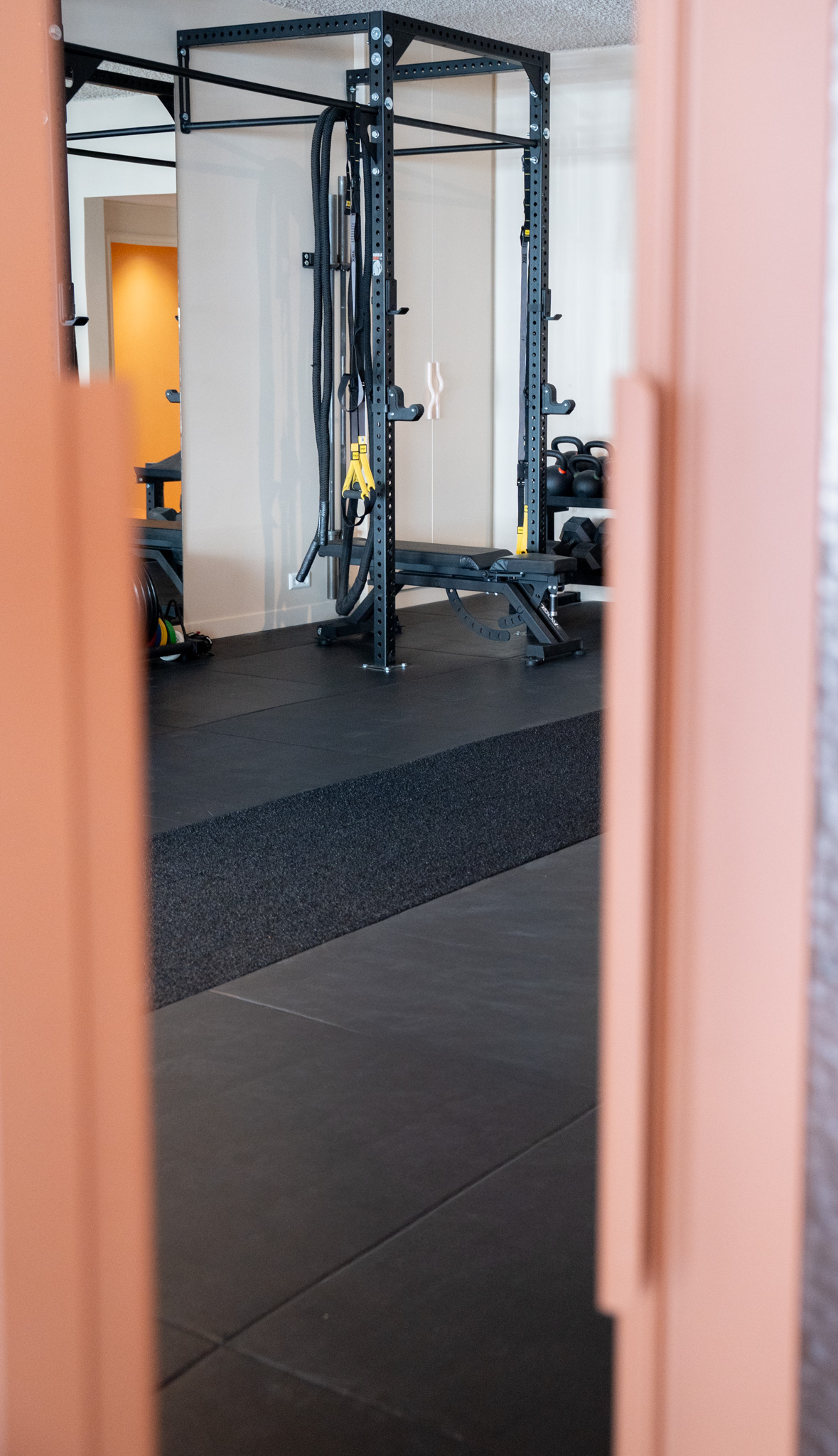 freddies-studio-bussum-doorkijk-tussen-glazen-deuren-naar-power-rack-met-trx-banden-en-kettlebells
