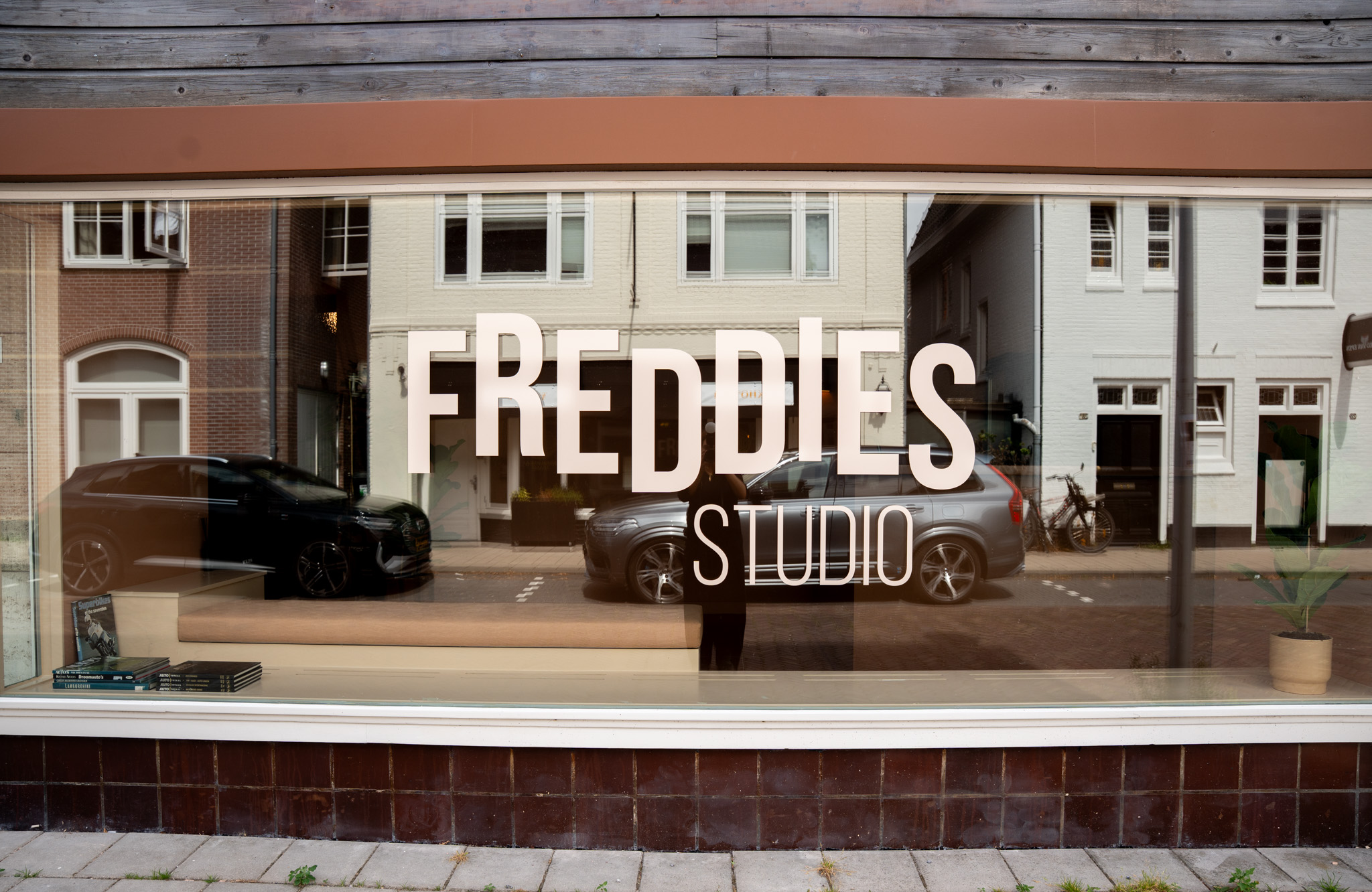 freddies studio bussum etalageraam met logo en spiegeling van straat en auto