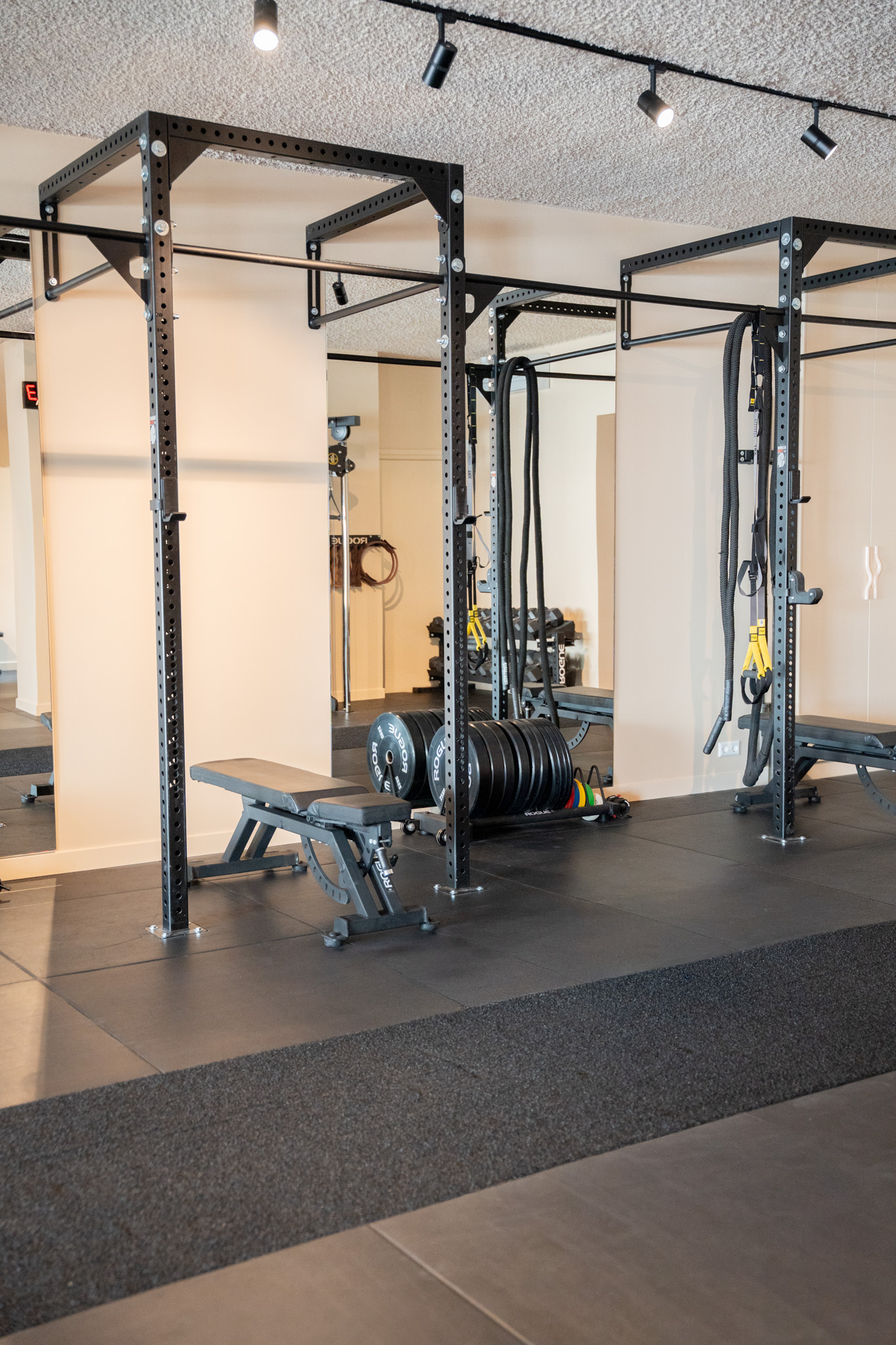 freddies-studio-bussum-fitnessruimte-met-power-racks-trx-banden-en-gewichtsschijven-bij-uitgang