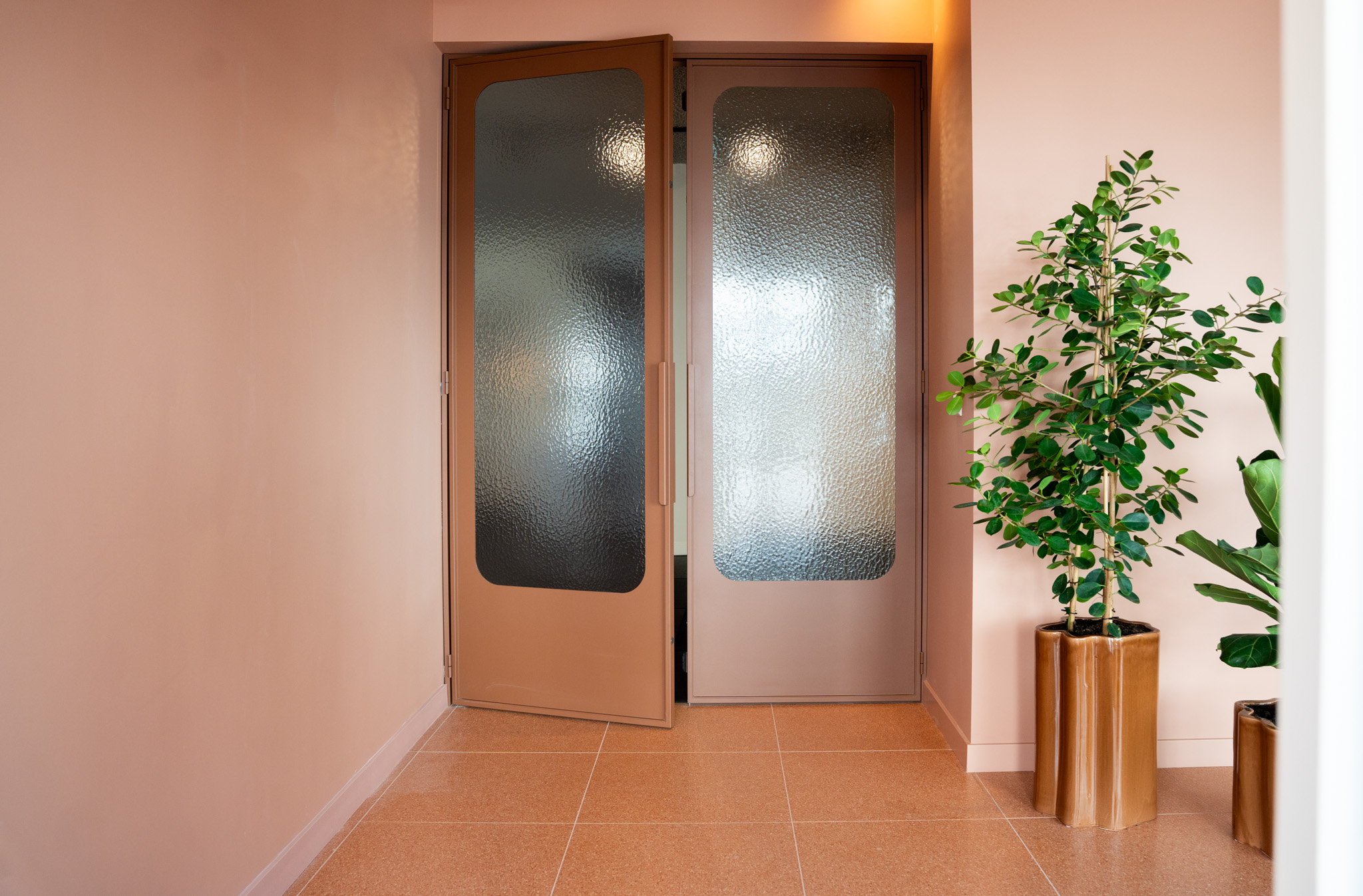 freddies studio bussum glazen entreedeuren met geribbeld glas en twee planten in koperen potten