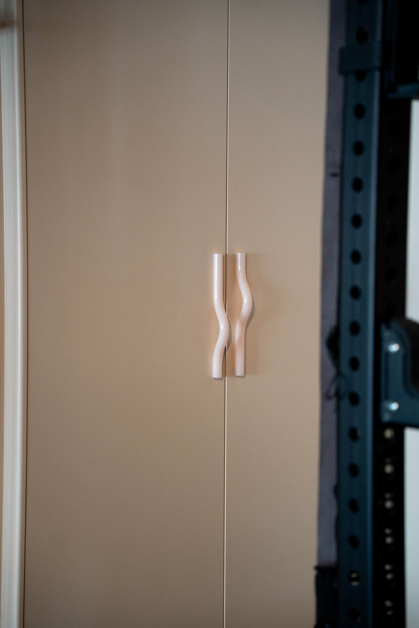 freddies-studio-bussum-golvende-witte-deurgreep-op-deur-met-power-rack-op-achtergrond