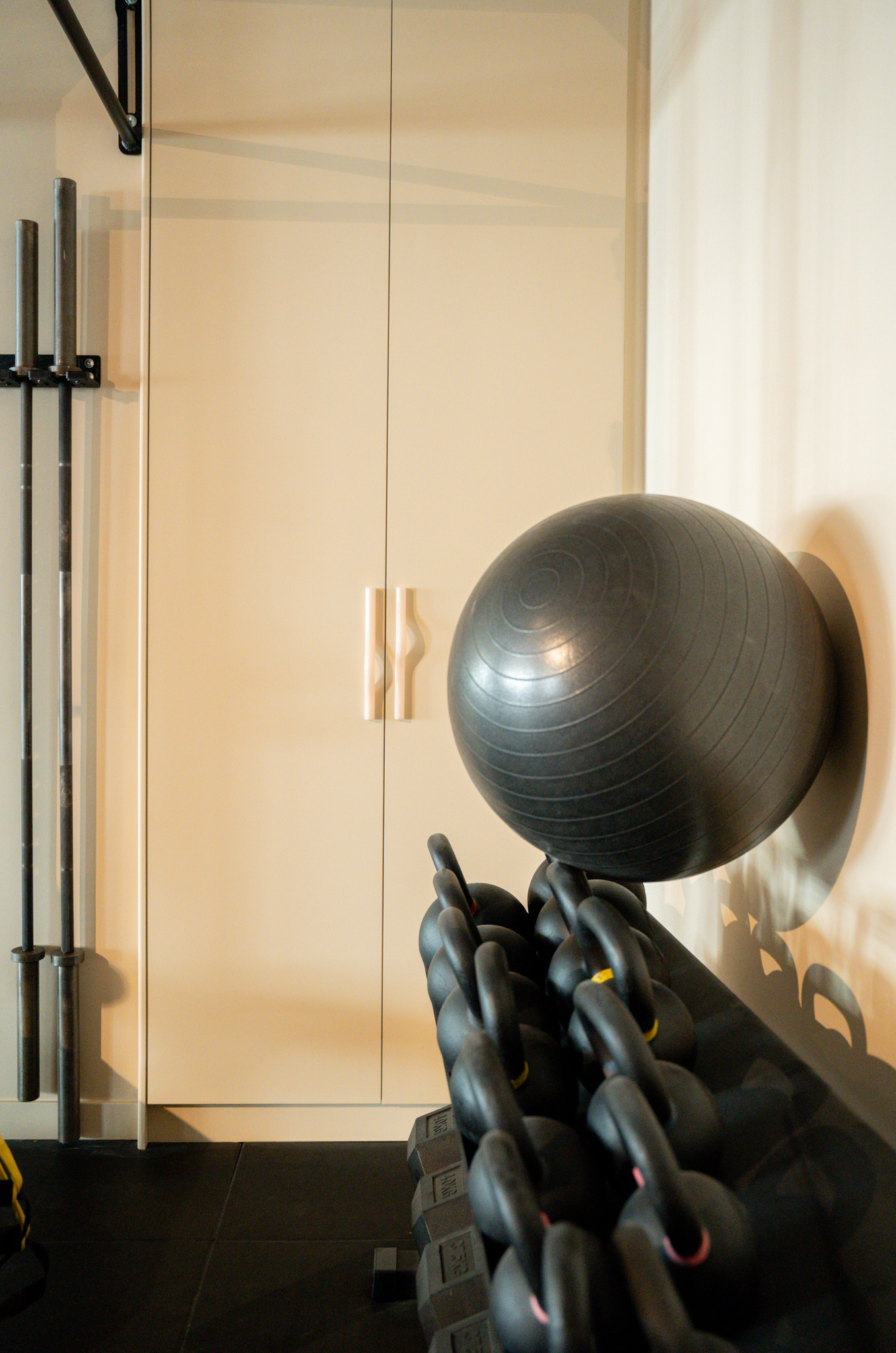 freddies-studio-bussum-golvende-witte-kastgrepen-naast-barbellhouder-en-fitnessbal