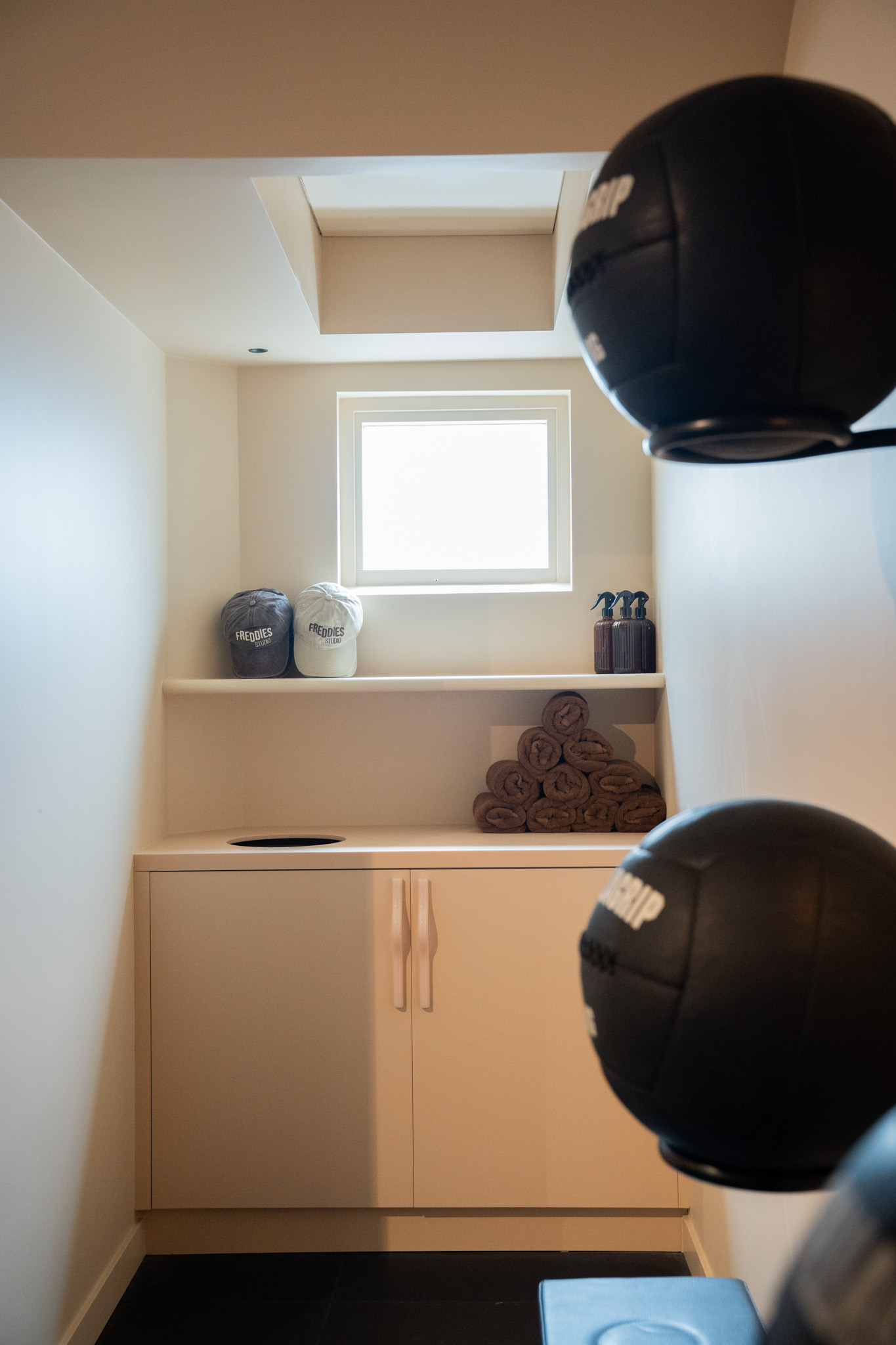 freddies-studio-bussum-kastje-met-petten-handdoeken-en-medicijnbal-op-voorgrond-bij-dakraam