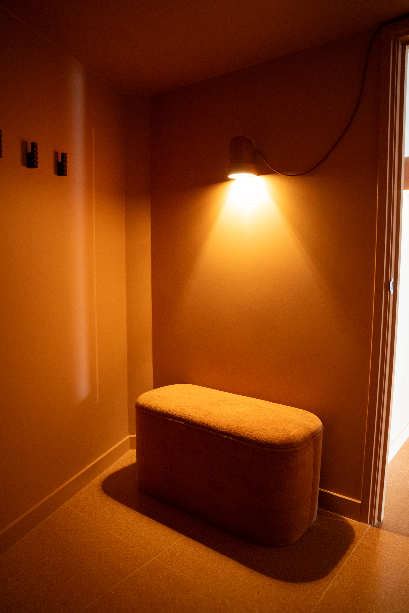 freddies-studio-bussum-kleedruimte-hoek-terracotta-bankje-wandlamp-met-kledinghaakjes