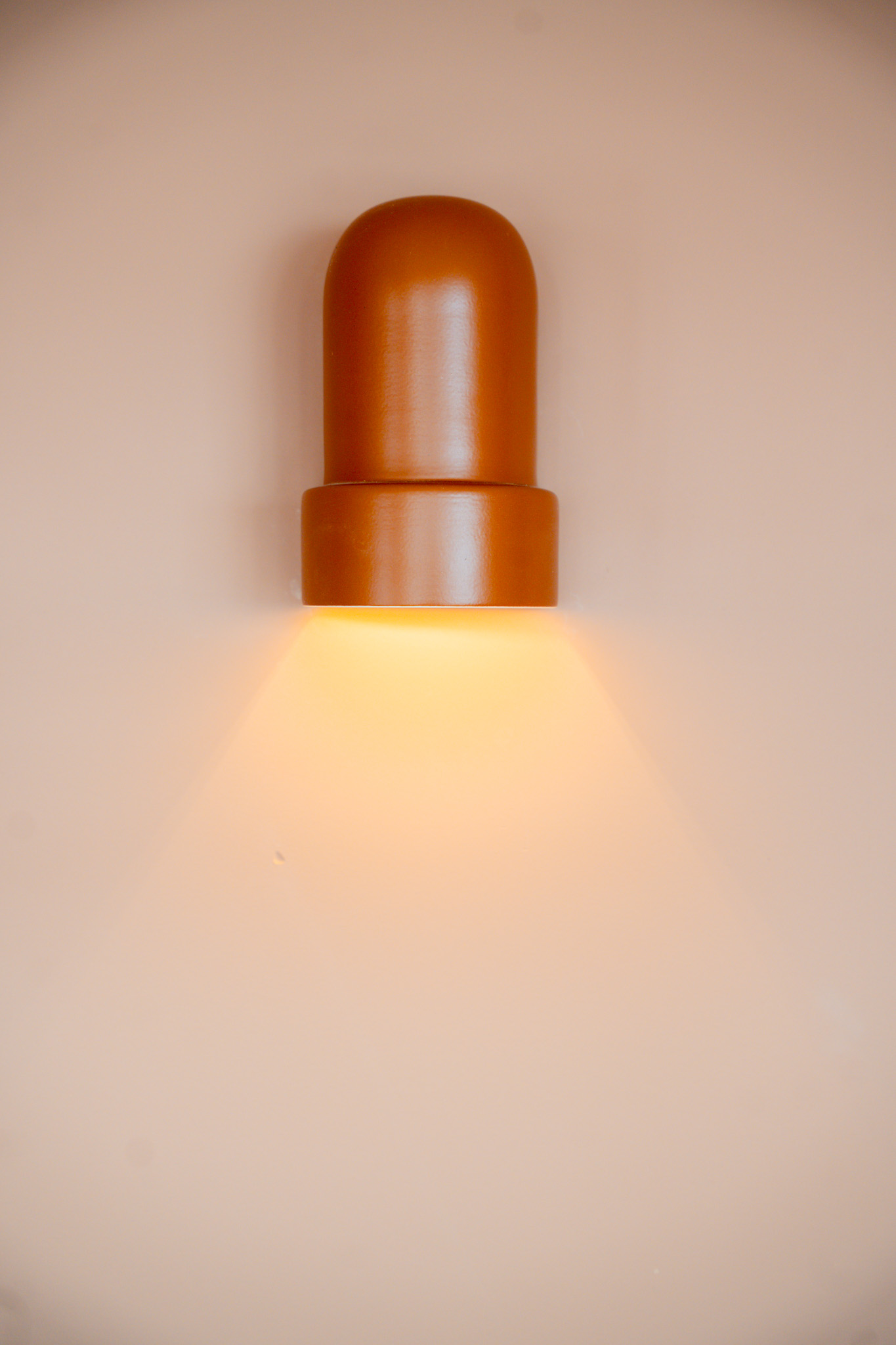 freddies-studio-bussum-terracotta-wandlamp-met-warm-licht-op-muur