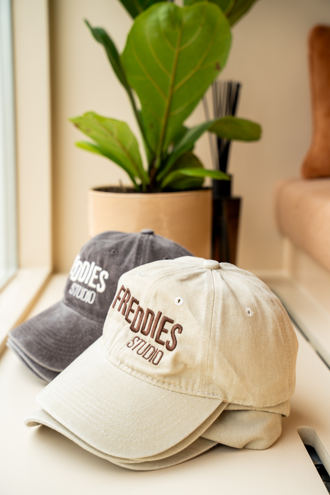 freddies-studio-bussum-twee-freddies-studio-petten-in-grijs-en-beige-met-plant-op-achtergrond