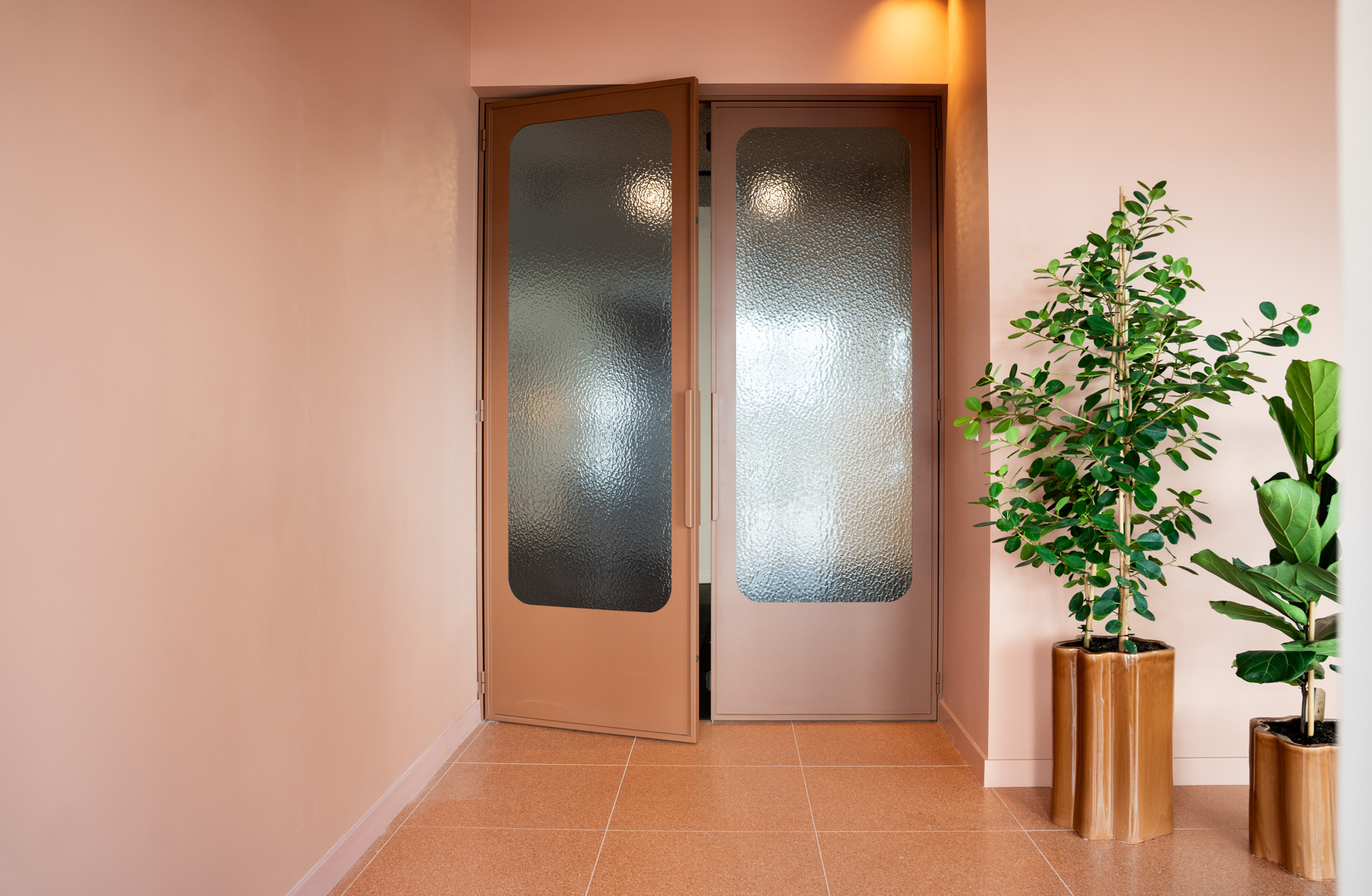 freddies studio bussum twee planten in golvende koperkleurige potten bij glazen deur