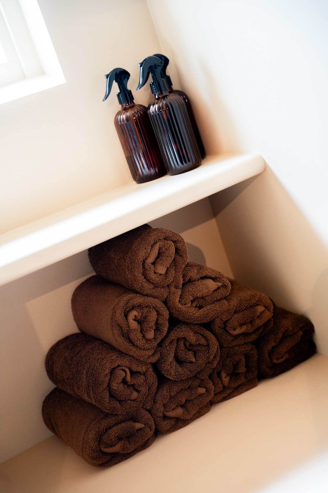 freddies-studio-bussum-verticale-opname-opgerolde-handdoeken-met-sprayflacons-op-plank