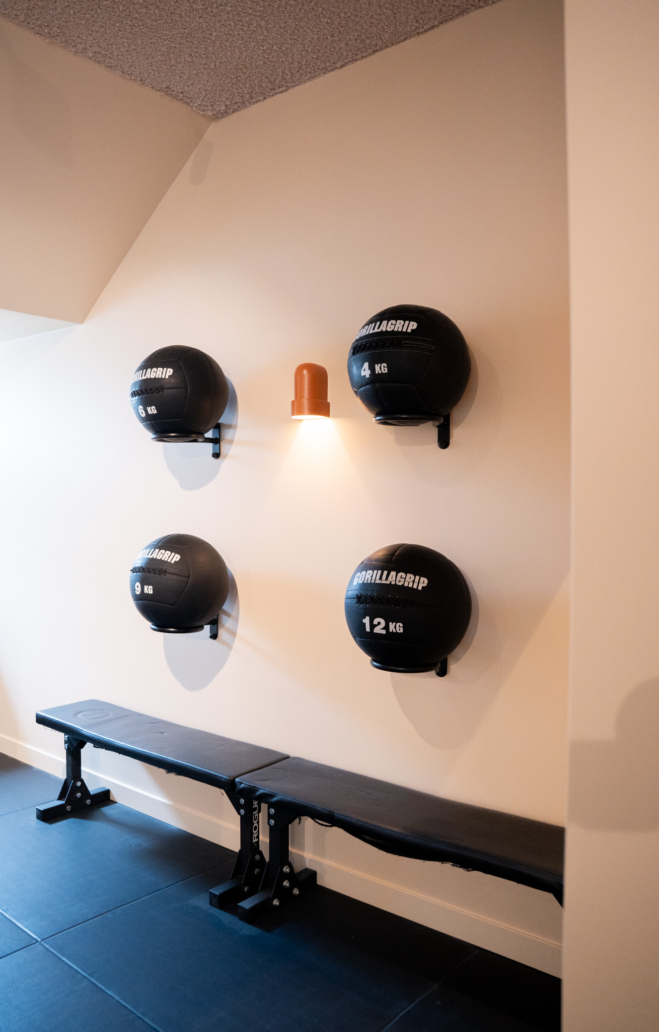 freddies-studio-bussum-vier-gorillagrip-medicijnballen-aan-muur-met-wandlamp-en-fitnessbank
