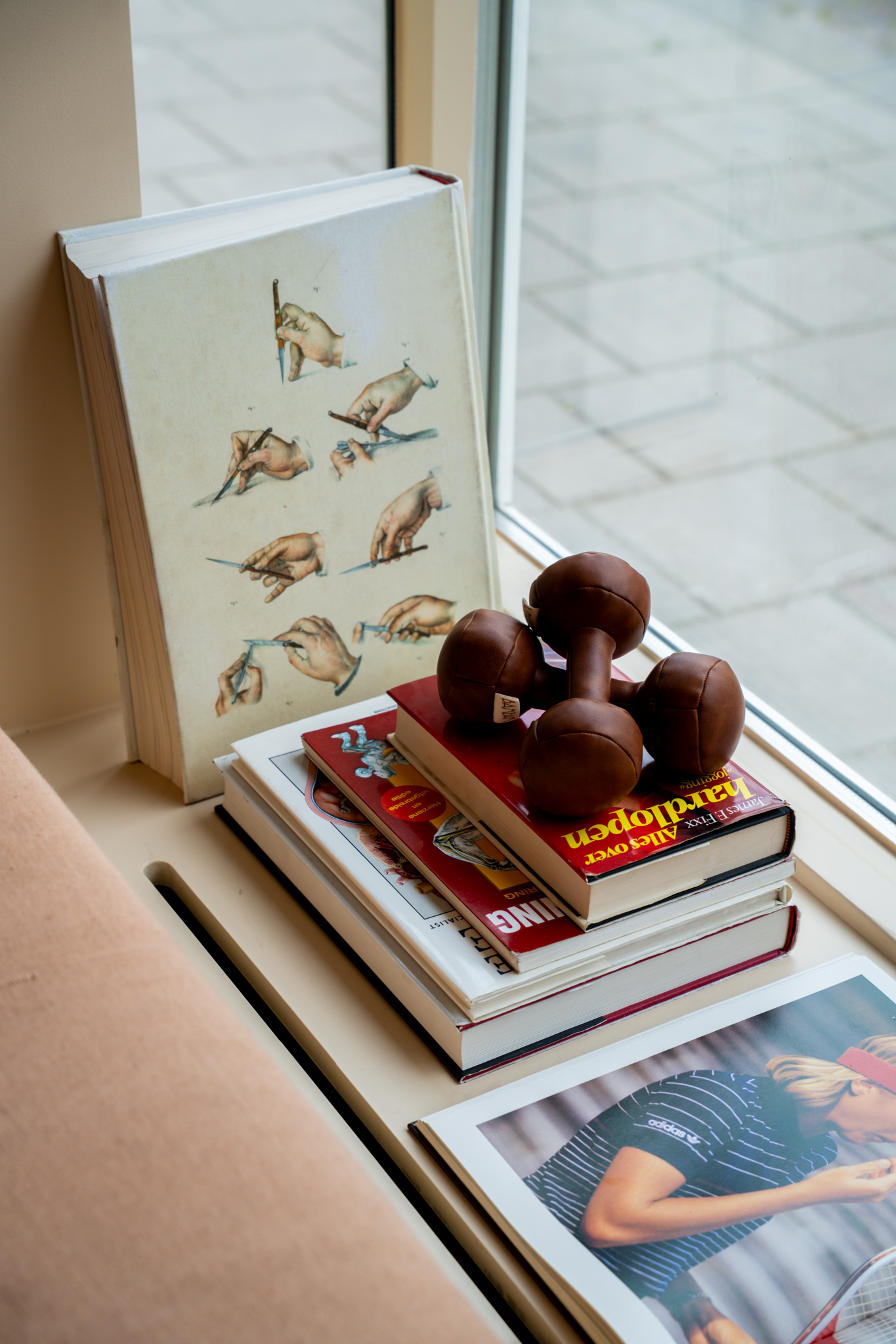 freddies-studio-bussum-vintage-leren-dumbbells-op-stapel-boeken-bij-raam